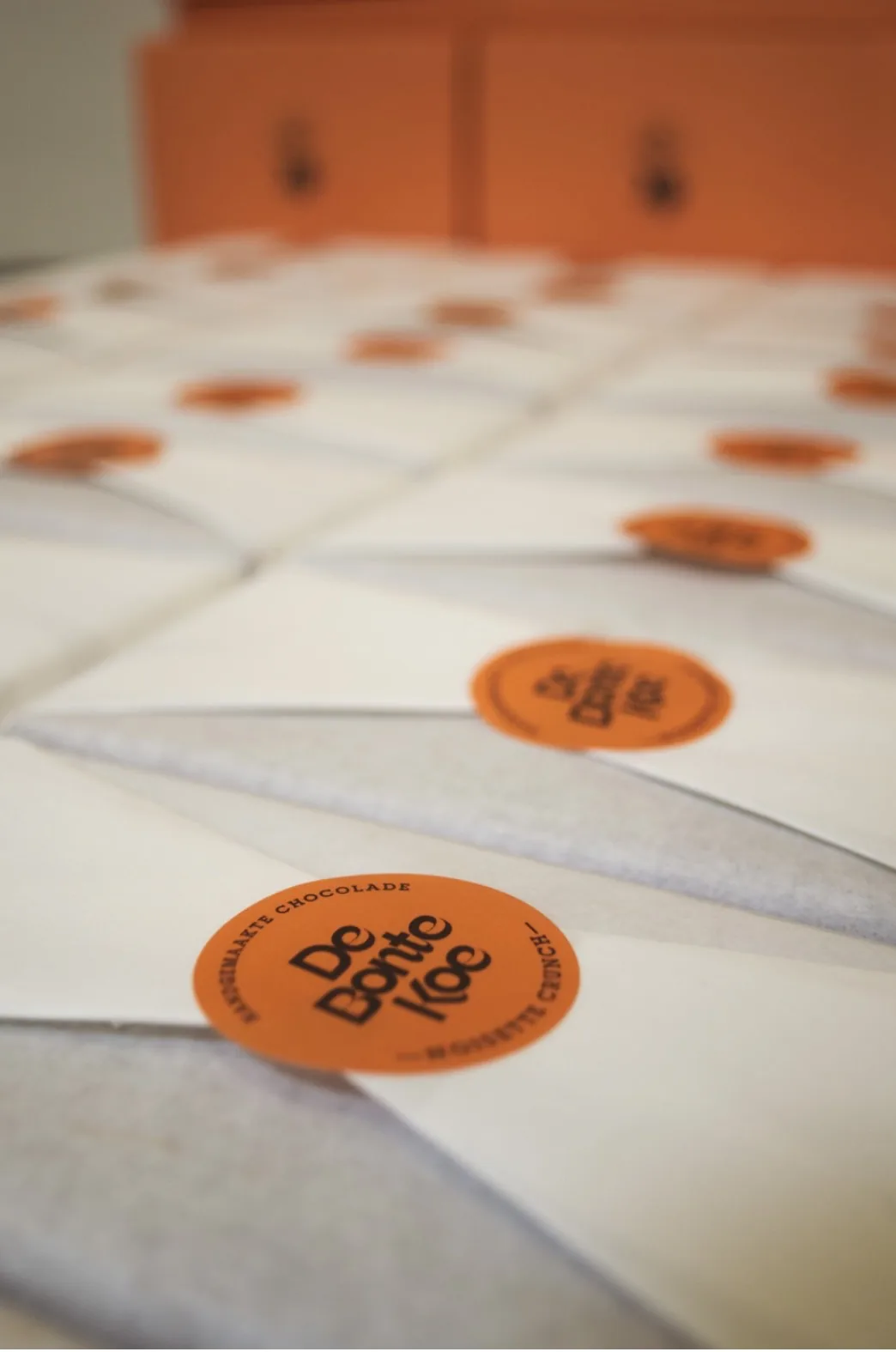 Rows of envelopes sealed with orange De Bonte Koe stickers.