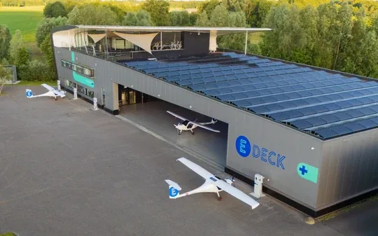 The E-Deck base from above: a hangar with a solar roof and electric planes outside.