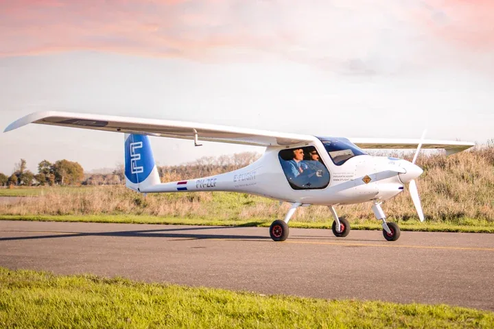 An E-Flight Academy electric training plane taxiing along a runway at sunset.