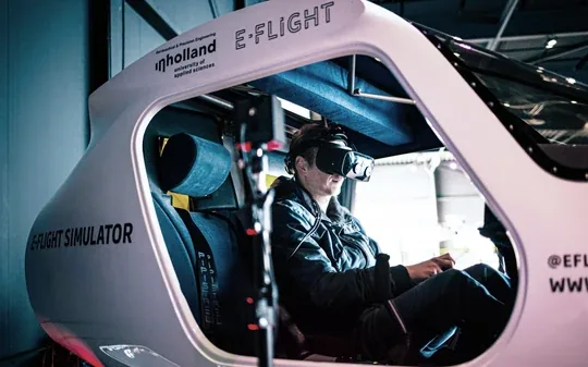A student in the E-Flight flight simulator, wearing a VR headset.