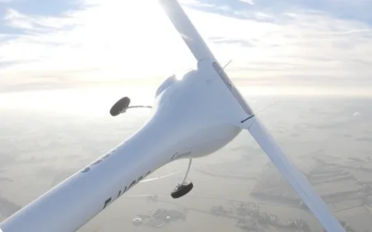 The wing of an electric training plane above the clouds.